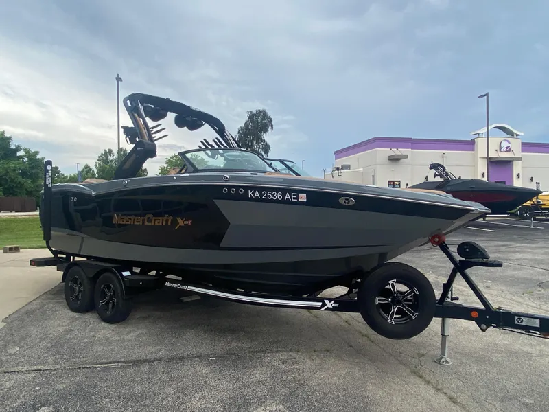 Slide: The Image of 2022 MasterCraft XStar boat on trailer, parked outdoors, overcast sky. - 4