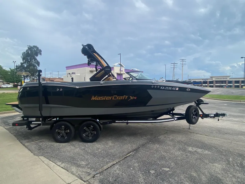 Slide: The Image of 2022 MasterCraft XStar boat on trailer, parked outdoors under cloudy sky. - 5