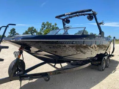 Slide: The Image of 2025 ATX Surf Boats 24 Type-S on trailer, sleek black design, outdoor setting. - 1