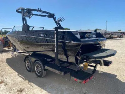 Slide: The Image of 2025 ATX Surf Boats 24 Type-S on trailer, sleek black design, outdoor setting. - 2
