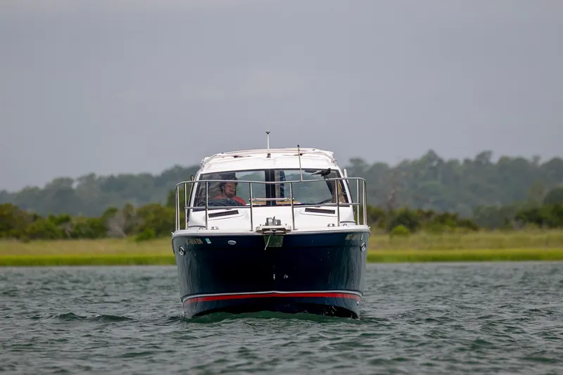 Slide: The Image of 2020 Cutwater C-24 boat cruising on a calm lake with lush green shoreline. - 1