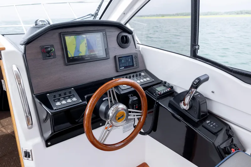 Slide: The Image of 2020 Cutwater C-24 helm with navigation controls and wooden steering wheel on open water. - 15