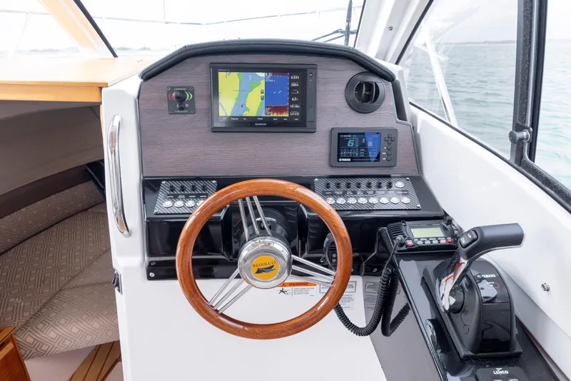Slide: The Image of 2020 Cutwater C-24 helm with navigation screens, wooden steering wheel, and control panel. - 16