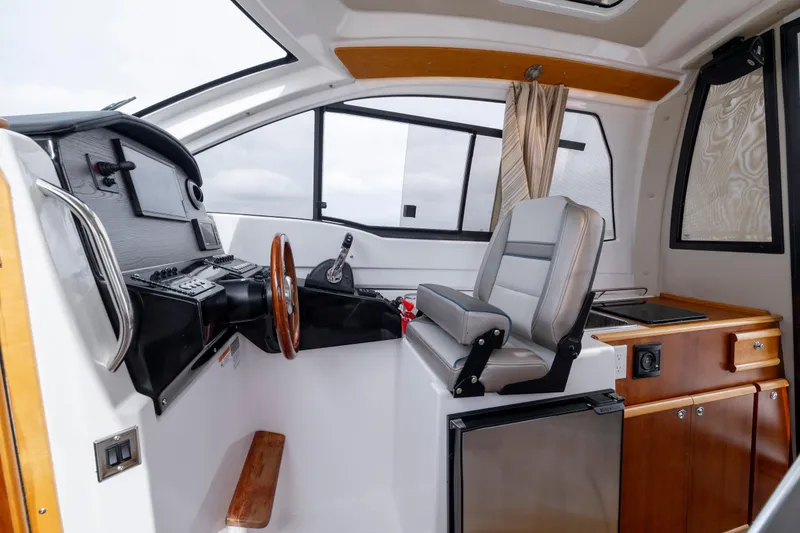 Slide: The Image of 2020 Cutwater C-24 boat interior with helm, captain's chair, and kitchenette. - 17