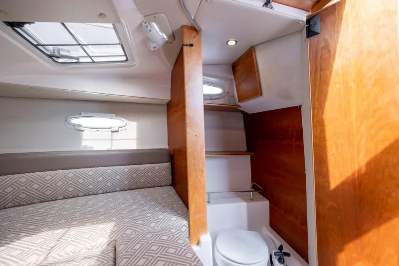 Slide: The Image of 2020 Cutwater C-24 cabin interior with bed, shelves, and compact bathroom. - 21