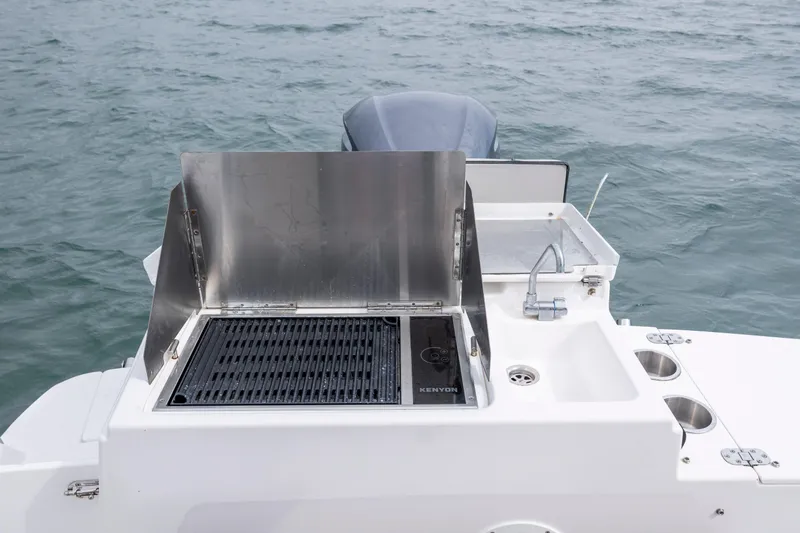 Slide: The Image of Outdoor grill and sink on 2020 Cutwater C-24 boat, set against ocean backdrop. - 32