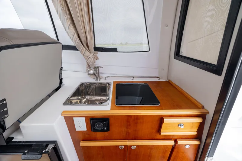 Slide: The Image of 2020 Cutwater C-24 boat interior with compact kitchen, sink, and wooden cabinetry. - 7