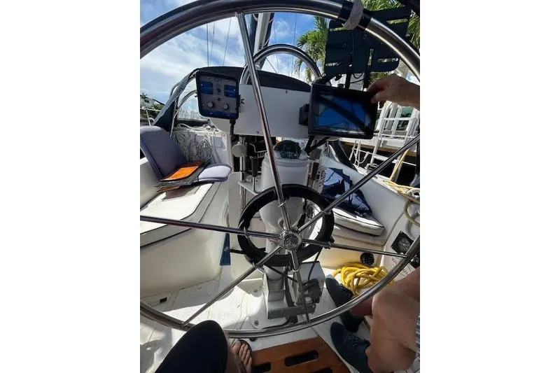 Slide: The Image of 1987 Hunter 35 sailboat docked, featuring cockpit view with palm trees and waterfront homes. - 16