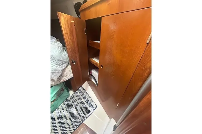 Slide: The Image of Wooden interior cabinet in a 1987 Hunter 35 sailboat, with open doors and visible shelving. - 39