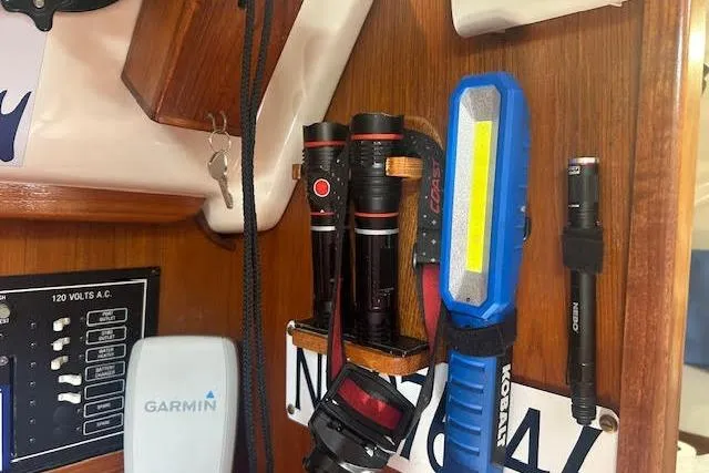 Slide: The Image of Flashlights and tools mounted on a wooden panel inside a 1987 Hunter 35 boat. - 42