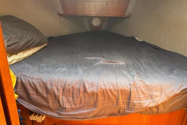 Slide: The Image of Cozy cabin bed inside a 1987 Hunter 35 sailboat, featuring wooden accents and soft bedding. - 59
