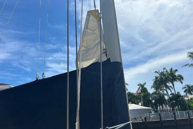 Slide: The Image of 1987 Hunter 35 sailboat with sails, docked under a clear blue sky. - 61