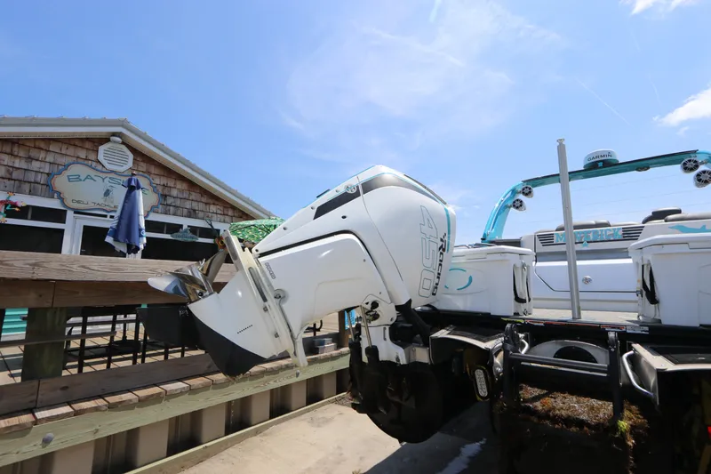 Slide: The Image of 2022 Tahoe Pontoon Grand Tahoe Twin Elite M2785 with powerful outboard motor, docked near a deli. - 3