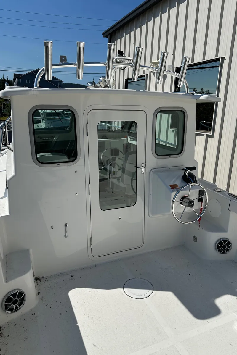 Slide: The Image of Parker 2420 Sport Cabin 2025 boat with white exterior and fishing rod holders. - 12