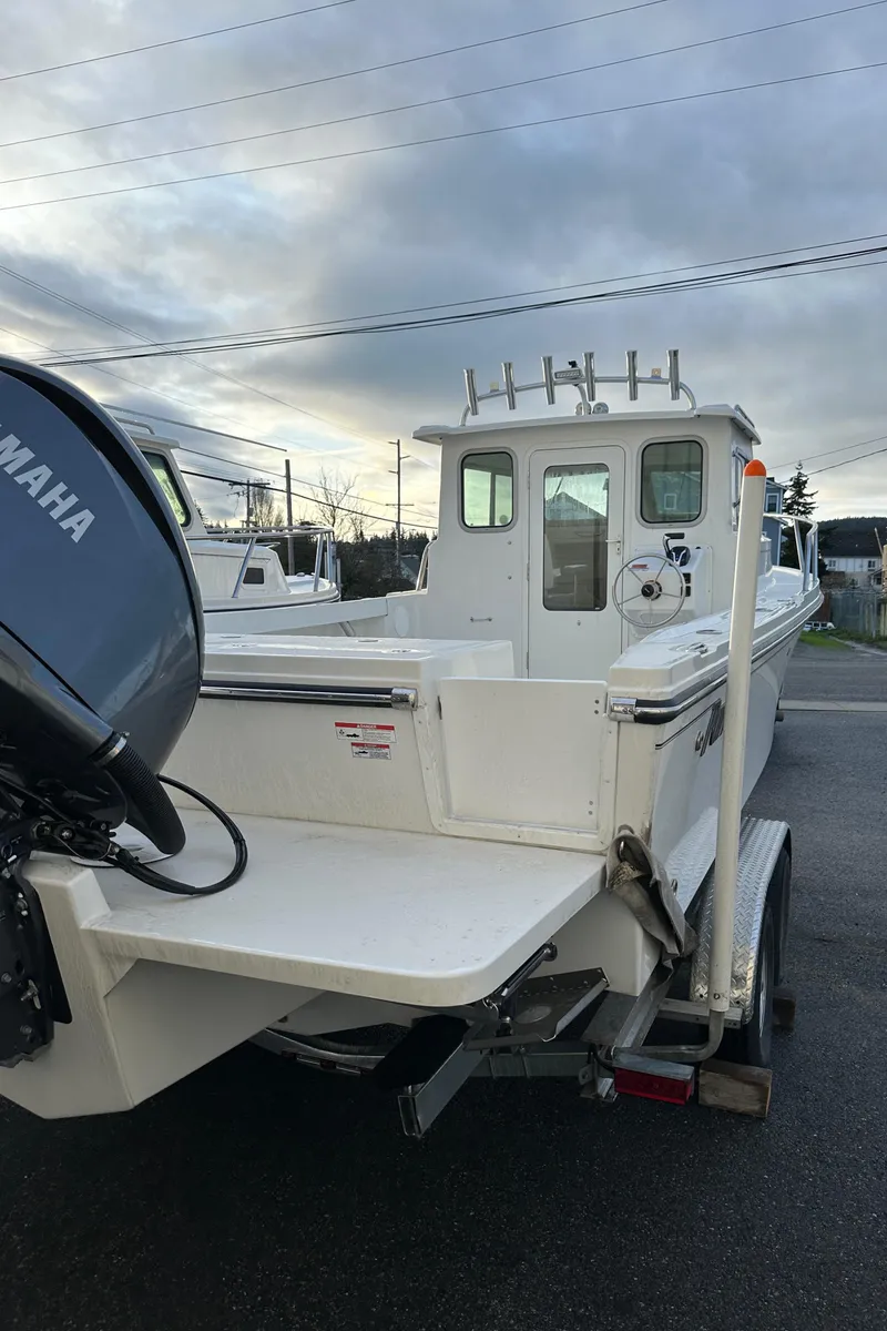 Slide: The Image of 2025 Parker 2420 Sport Cabin boat with Yamaha engine on a trailer, under cloudy sky. - 3