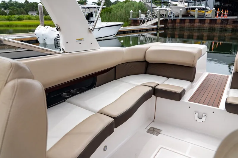 Slide: The Image of 2013 Regal 2700 ES Bowrider interior with beige seating and wood accents, docked by water. - 13
