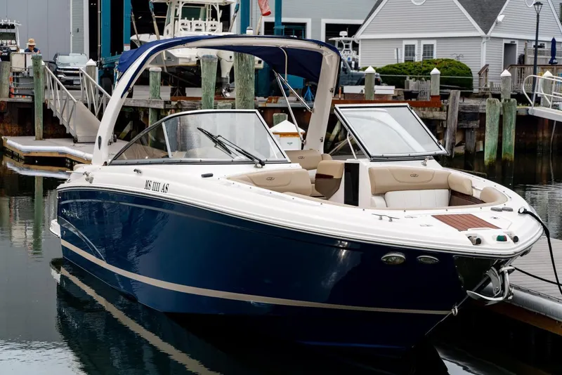 Slide: The Image of 2013 Regal 2700 ES Bowrider boat docked in marina, featuring sleek blue design. - 2