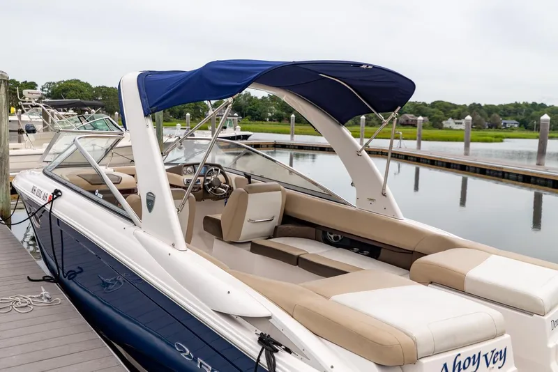 Slide: The Image of 2013 Regal 2700 ES Bowrider docked, featuring blue canopy and beige seating. - 4
