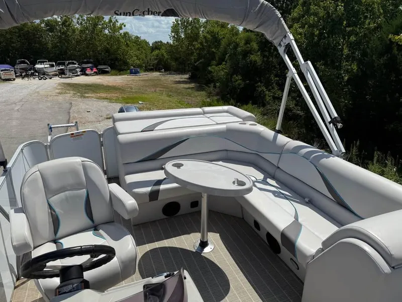 Slide: The Image of 2018 G3 V20C pontoon boat interior with seating and table, parked near trees. - 12