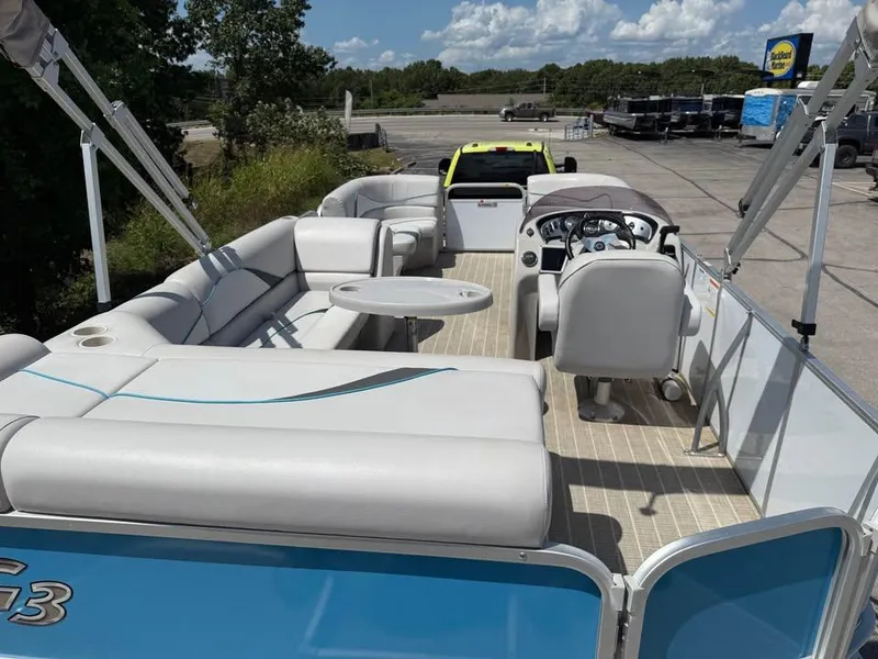 Slide: The Image of 2018 G3 V20C pontoon boat with spacious seating and steering console, parked outdoors. - 6