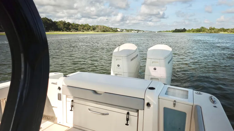 Slide: The Image of 2023 Scout 377 LXF boat with dual Mercury engines on a scenic waterway. - 16