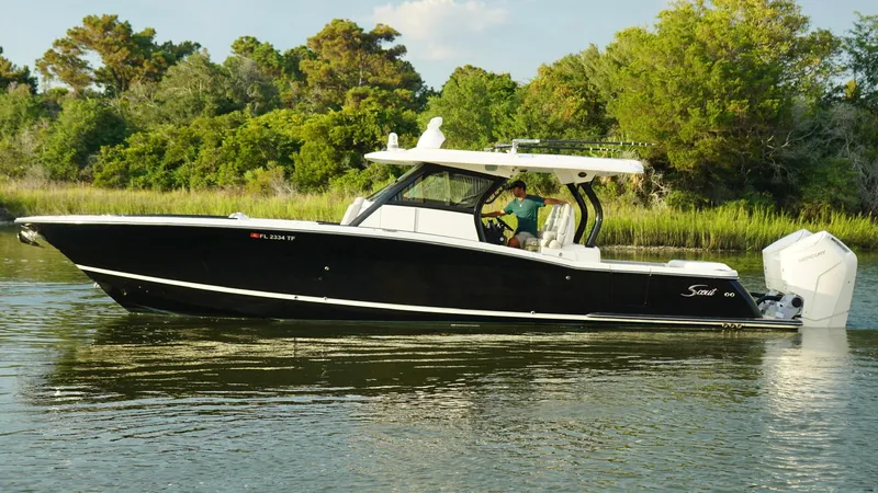 Slide: The Image of 2023 Scout 377 LXF boat cruising on a calm river with lush greenery. - 2