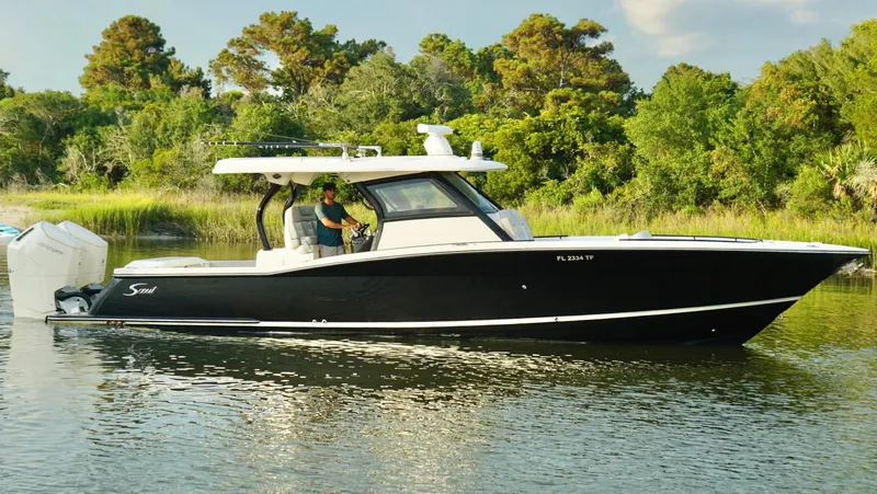Slide: The Image of 2023 Scout 377 LXF boat cruising on a calm river with lush greenery. - 3
