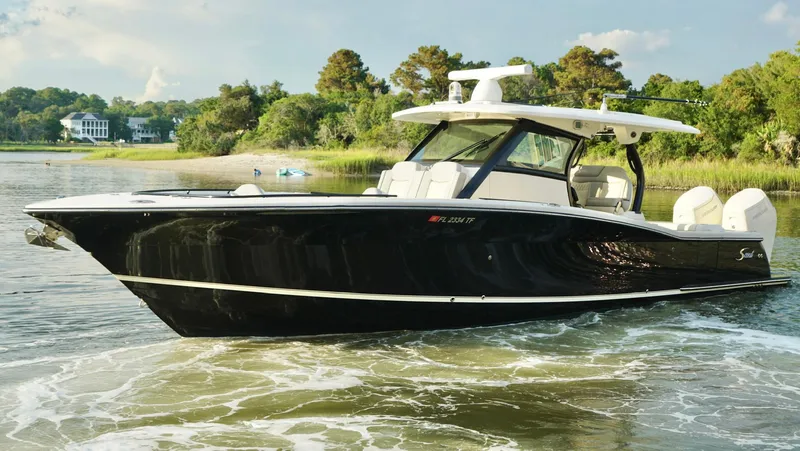 Slide: The Image of 2023 Scout 377 LXF boat cruising on a scenic waterway. - 5