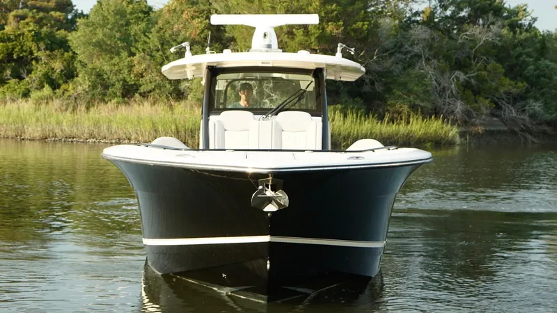 Slide: The Image of 2023 Scout 377 LXF boat on calm water, surrounded by lush greenery. - 6