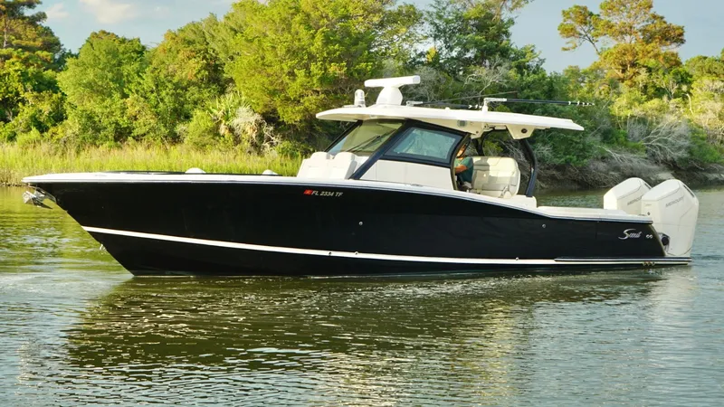 Slide: The Image of 2023 Scout 377 LXF boat cruising on a calm river with lush greenery. - 7