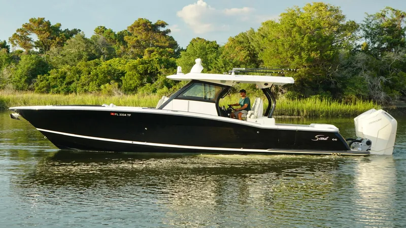 Slide: The Image of 2023 Scout 377 LXF boat cruising on a calm river with lush greenery. - 8