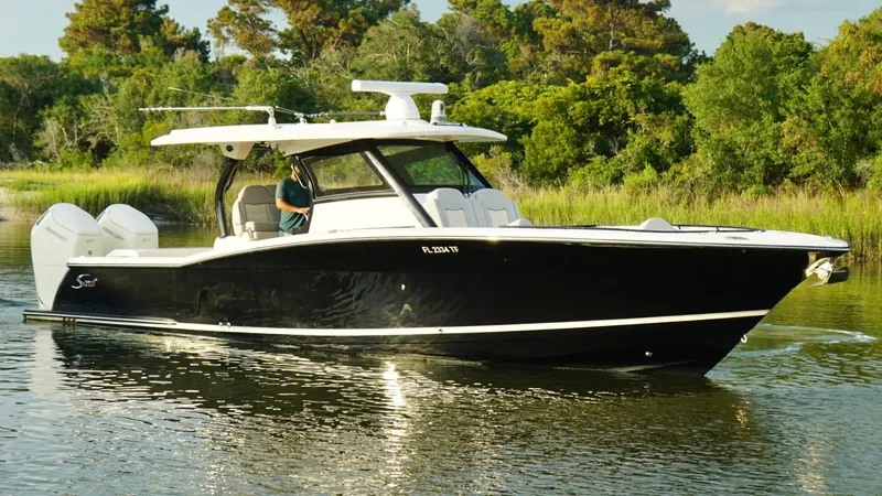 Slide: The Image of 2023 Scout 377 LXF boat cruising on a calm river with lush greenery in the background. - 9