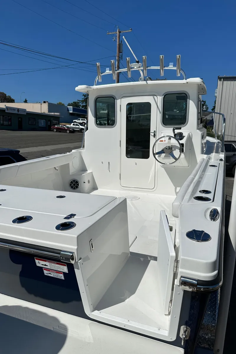Slide: The Image of 2026 Parker 2220 boat, white deck, steering wheel, rod holders, clear sky background. - 23