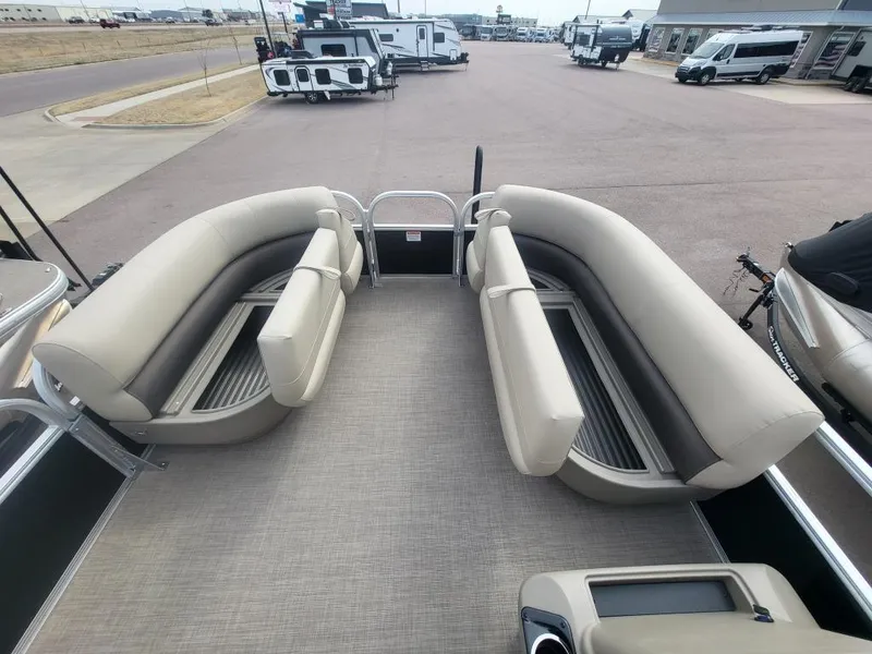 Slide: The Image of 2025 Sun Tracker Party Barge 16 DLX interior with beige seating, parked in a dealership lot. - 11
