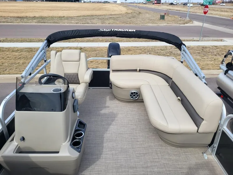 Slide: The Image of 2025 Sun Tracker Party Barge 16 DLX interior with beige seating and steering console. - 16