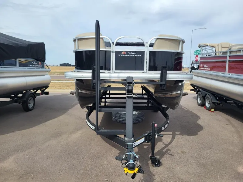 Slide: The Image of 2025 Sun Tracker Party Barge 16 DLX pontoon boat on trailer, parked outdoors. - 5