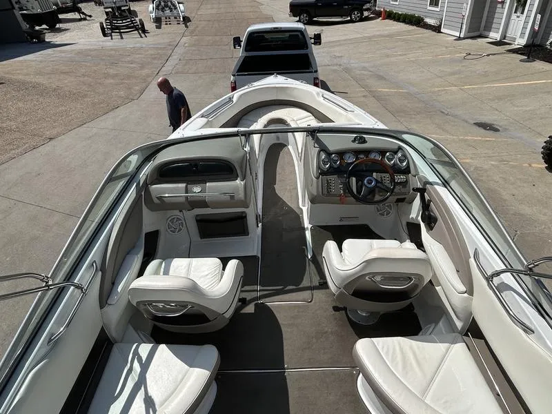 Slide: The Image of 2006 Cobalt 250 boat interior with white seating and dashboard, parked near a truck. - 11