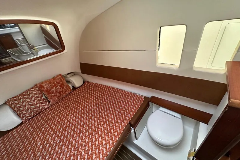 Slide: The Image of 2017 Edgewater 368CC cabin interior with bed, wooden cabinetry, and compact toilet. - 17