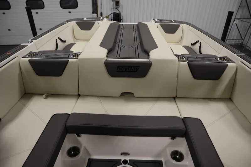 Slide: The Image of 2025 Heyday WT Surf boat interior with beige and black seating, cup holders, and sleek design. - 32