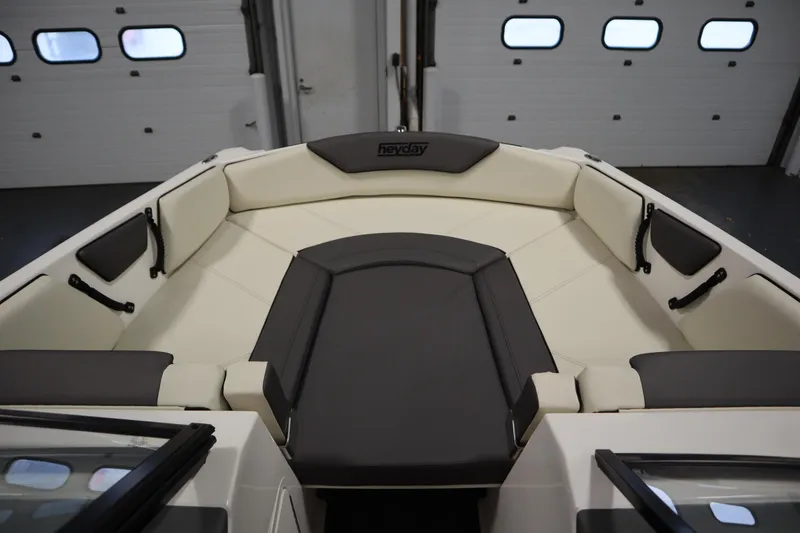 Slide: The Image of 2025 Heyday WT Surf boat interior with cushioned seating in a garage setting. - 10