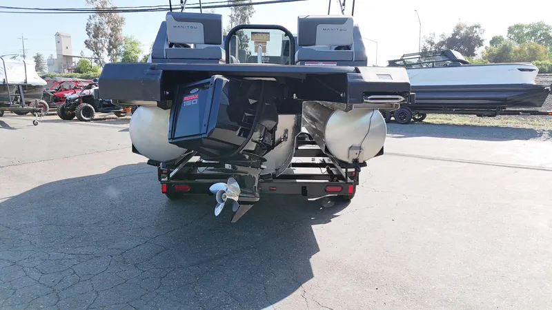 Slide: The Image of 2025 Manitou Cruise pontoon boat rear view with Rotax engine in a parking lot. - 14