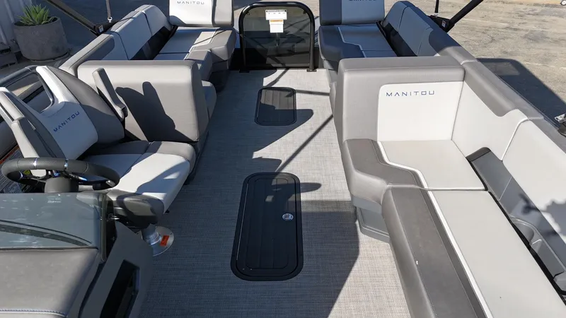 Slide: The Image of 2025 Manitou Cruise boat interior with gray seating and steering wheel, showcasing spacious design. - 17