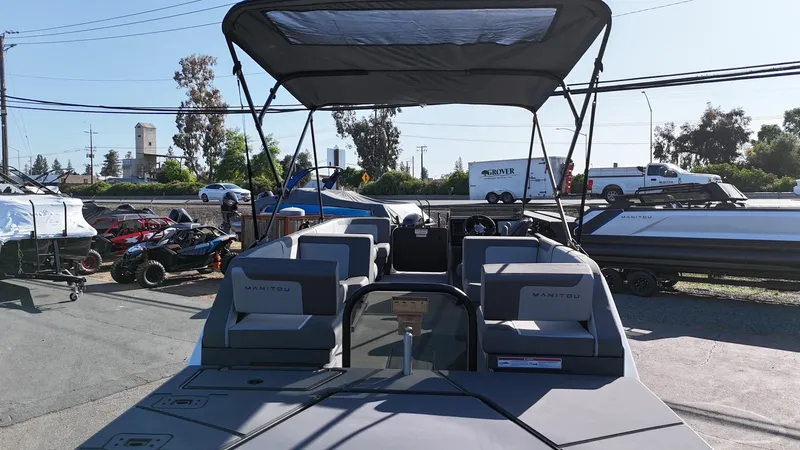 Slide: The Image of 2025 Manitou Cruise boat with canopy, parked outdoors on a sunny day. - 19