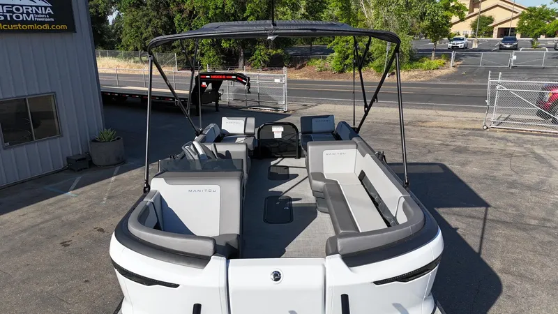 Slide: The Image of 2025 Manitou Cruise pontoon boat with spacious seating and canopy, parked outdoors. - 9
