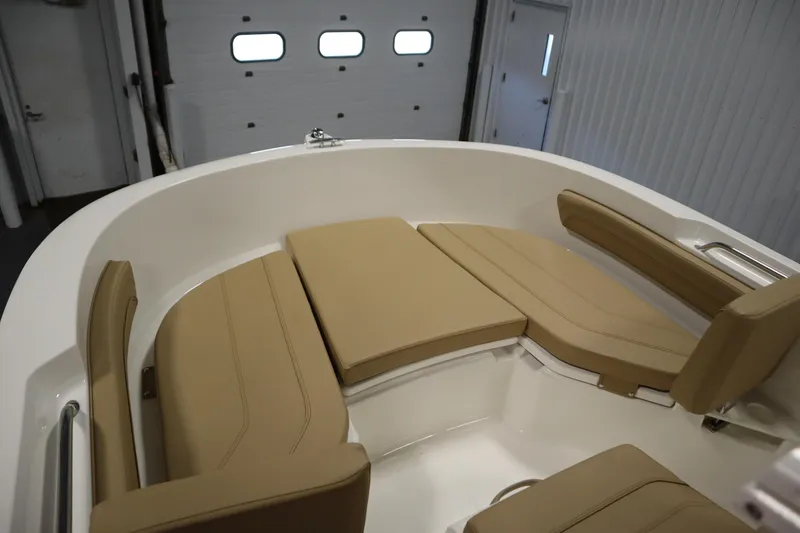 Slide: The Image of 2026 Bayliner 20 Cc Trophy boat interior with beige seating in a garage. - 10