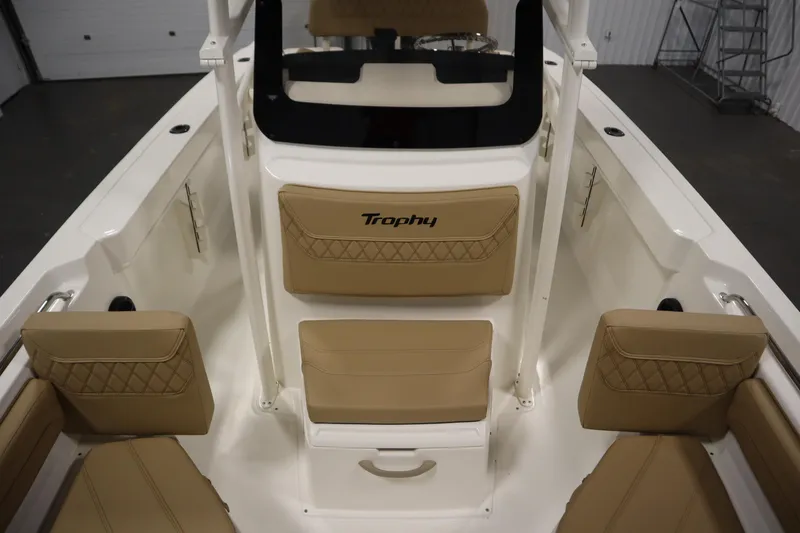 Slide: The Image of 2026 Bayliner 20 Cc Trophy boat interior with tan cushioned seating and "Trophy" logo. - 14