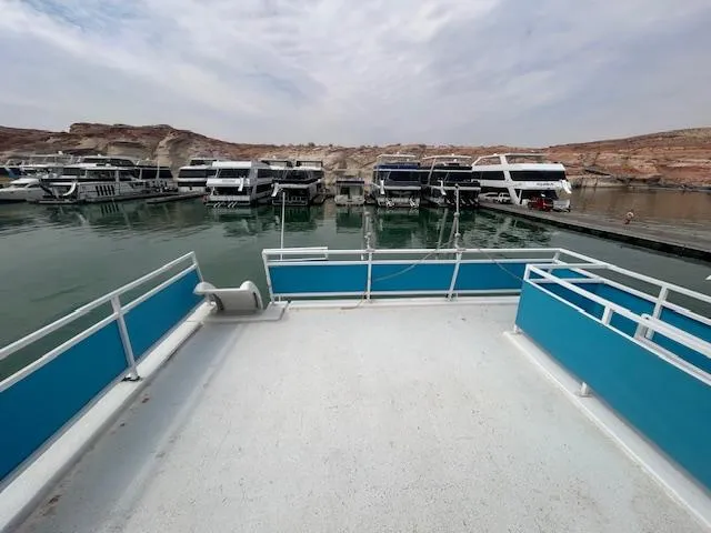 Slide: The Image of 1999 Skipperliner 59 x 14 houseboat docked, surrounded by similar boats, under a cloudy sky. - 25