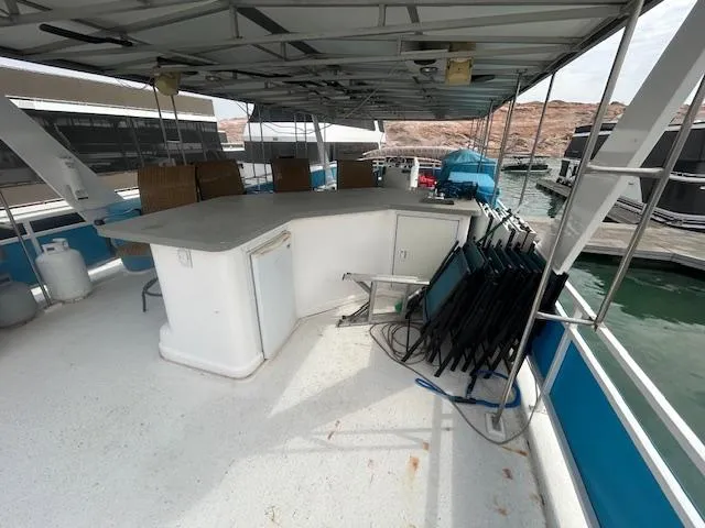 Slide: The Image of 1999 Skipperliner 59 x 14 houseboat deck with bar, chairs, and scenic marina view. - 26