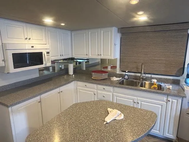 Slide: The Image of Modern kitchen in a 1999 Skipperliner 59 x 14 houseboat with white cabinets and granite countertops. - 8