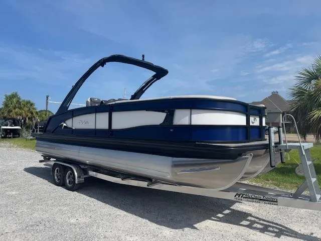 Slide: The Image of 2026 Barletta LUSSO 25 UCA pontoon boat on trailer, parked outdoors. - 2